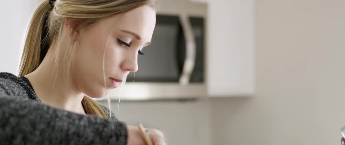 A woman is looking down stirring with a wooden spoon