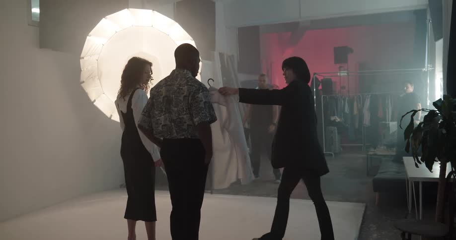 Man and woman model clothing under a bright light as a photographer takes photos of them