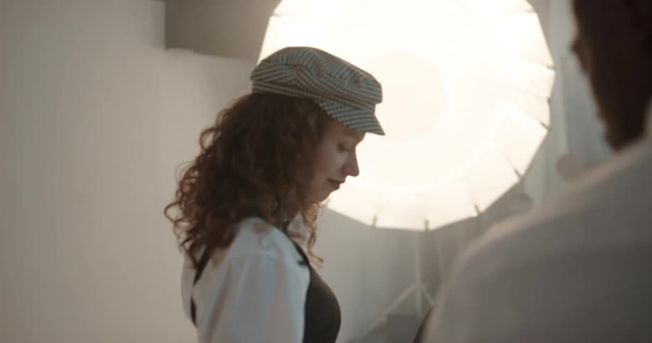 Dresser adjusts clothes worn by models standing on photography set under lighting