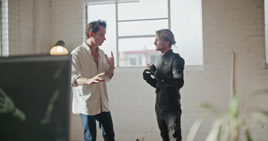Two men are communicating indoors near a window
