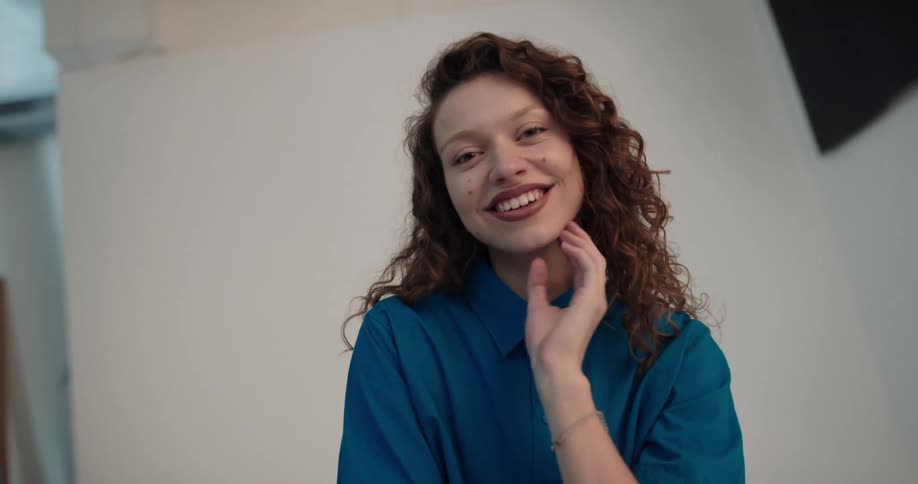 Young woman with curly hair modeling for the camera on a photoshoot under flashing lights