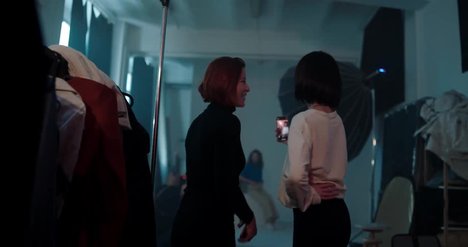 Two women looking at models posing for the camera in a fashion photo shoot