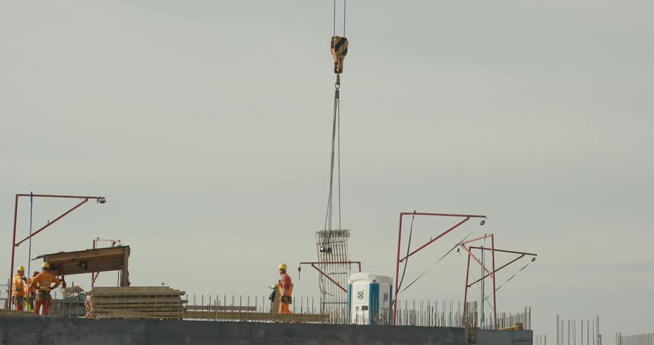 Group of workers wearing hardhats and protective equipment receive materials at a construction site