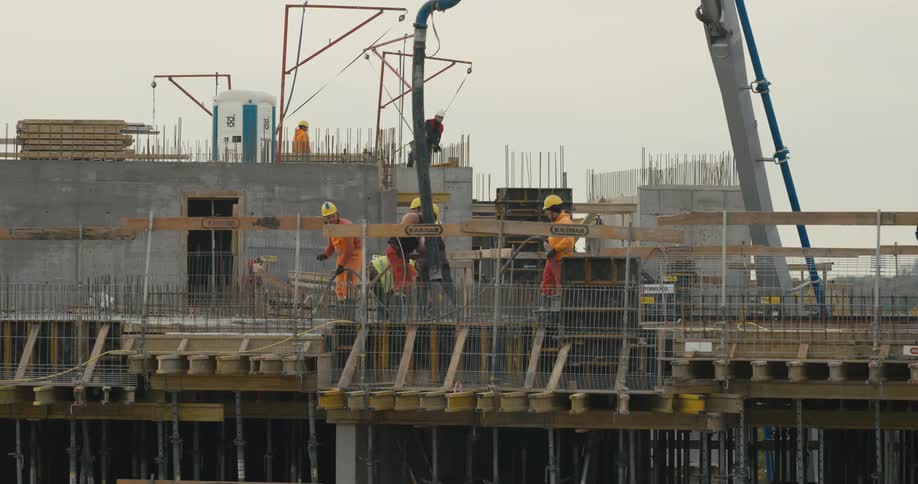 Construction workers move a large tube on a site
