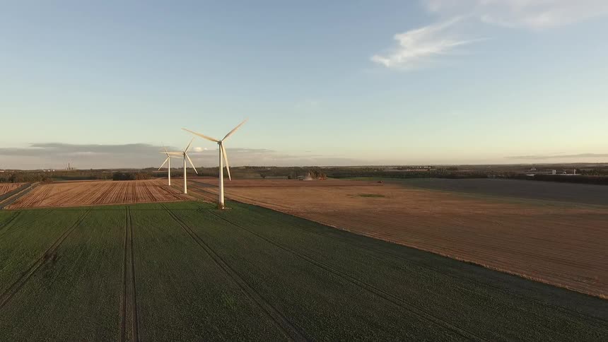 Windmills spin in green and yellow fields