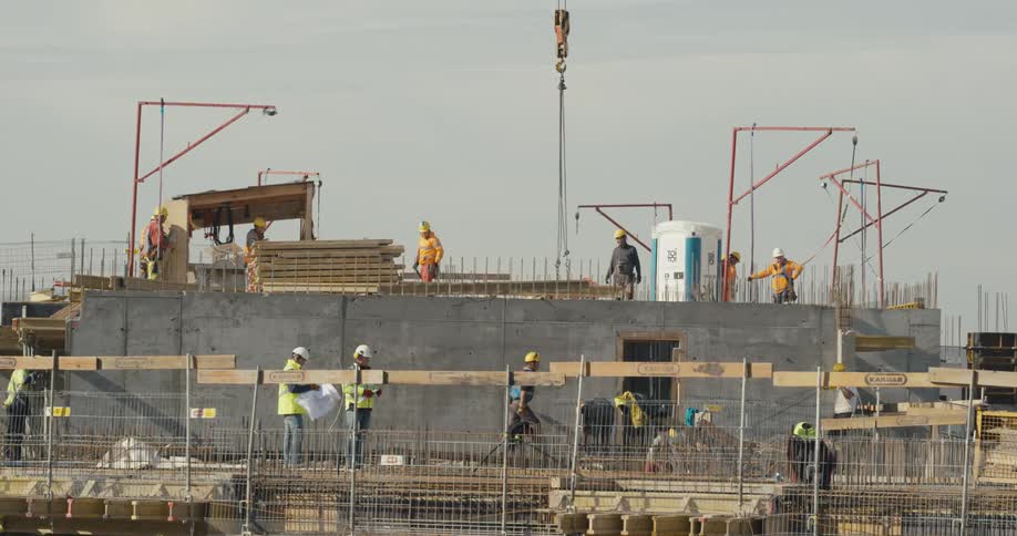 Group of workers wearing hardhats and protective equipment receive materials at a construction site