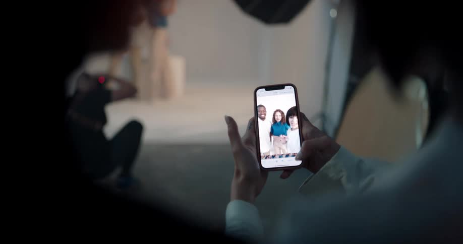 A woman is looking at her phone and people are waving to her