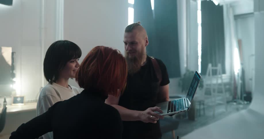 Three friends are talking and looking at a laptop