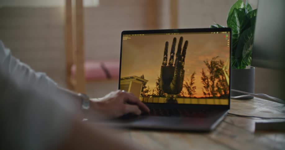 A man is looking at a laptop computer with an image of a hand on the screen