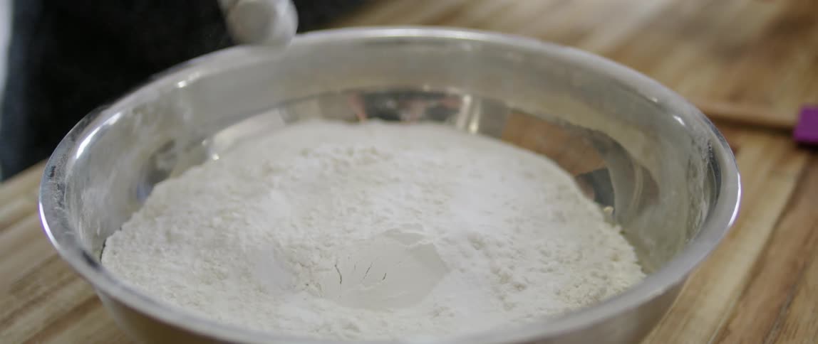 Ingredient being  added to a bowl of flour