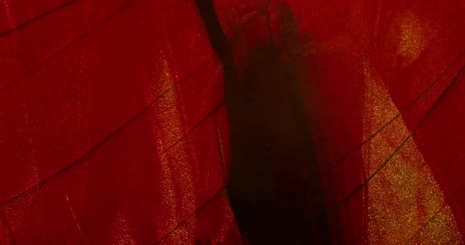 Gold particles coat folded crimson fabric