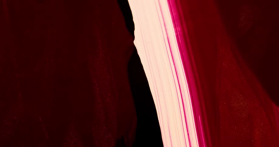 Thick blobs of liquid red ink flowing down a backlit translucent surface