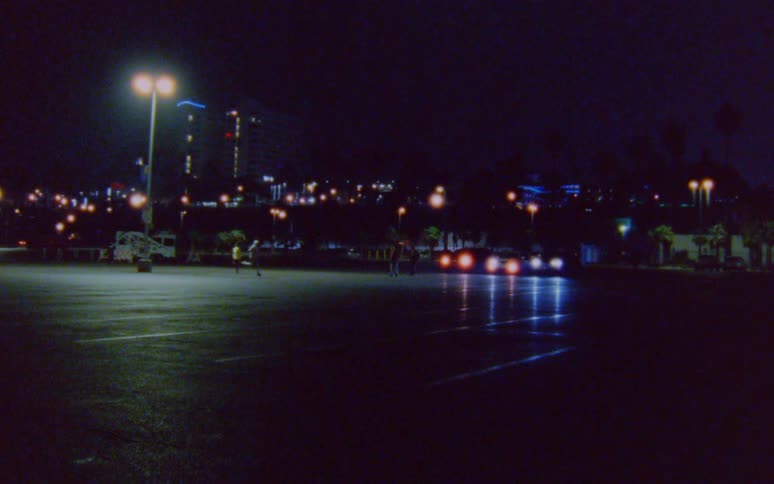 Two runners run towards each other in a city parking lot at night