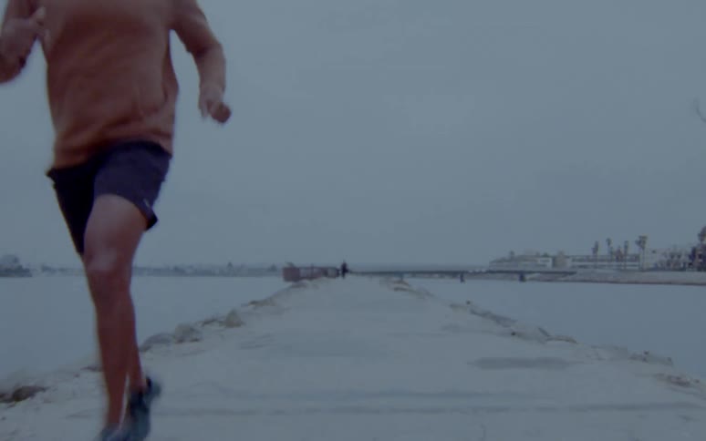 A group of men are jogging outdoors by a body of water