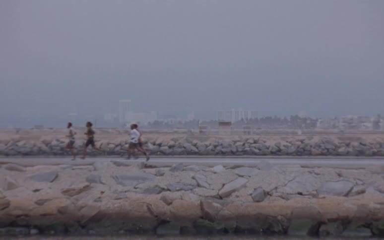 Four people run near the water