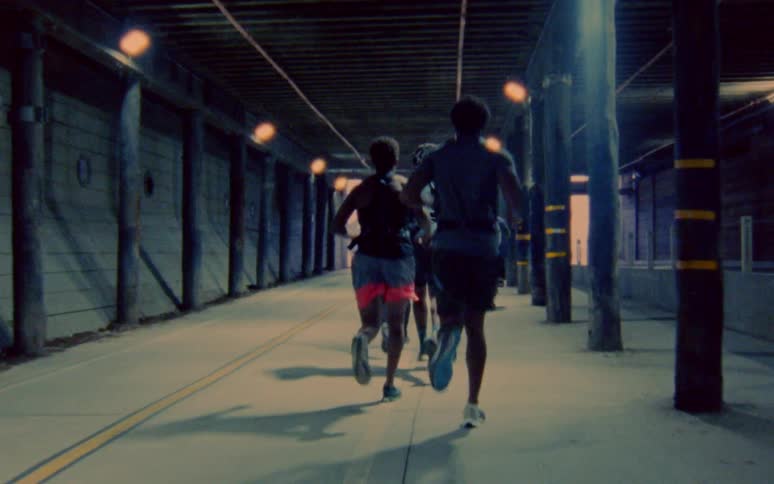 A group of men run through a tunnel as someone else bikes through