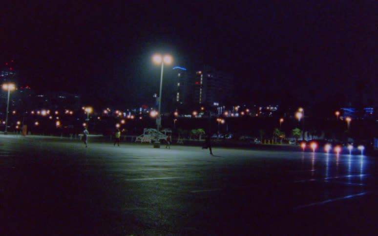 Group of four men jogging on a parking lot in the city at night caught on vintage film