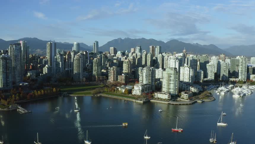 Aerial view of boats floating on a river in front of the the skyscrapers on Vancouver