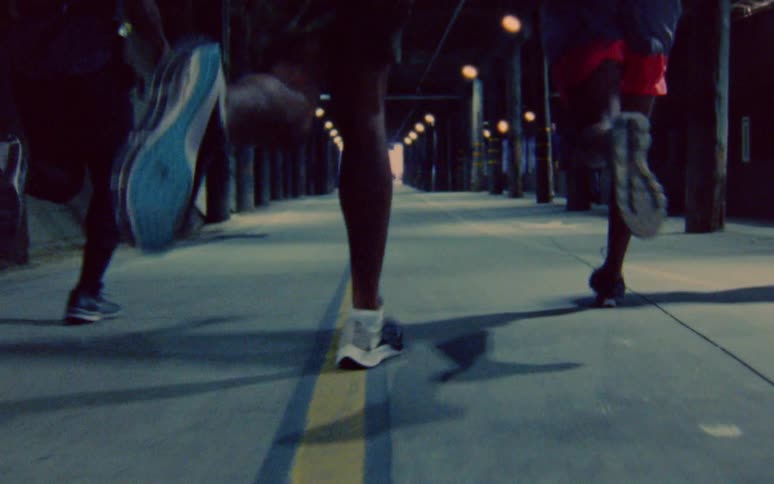 Four runners run side by side through a tunnel