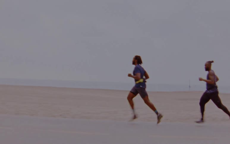 Three men are jogging on the coast at dusk