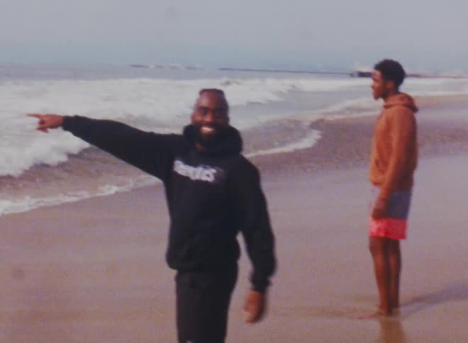 Footage of two men on the beach is displayed