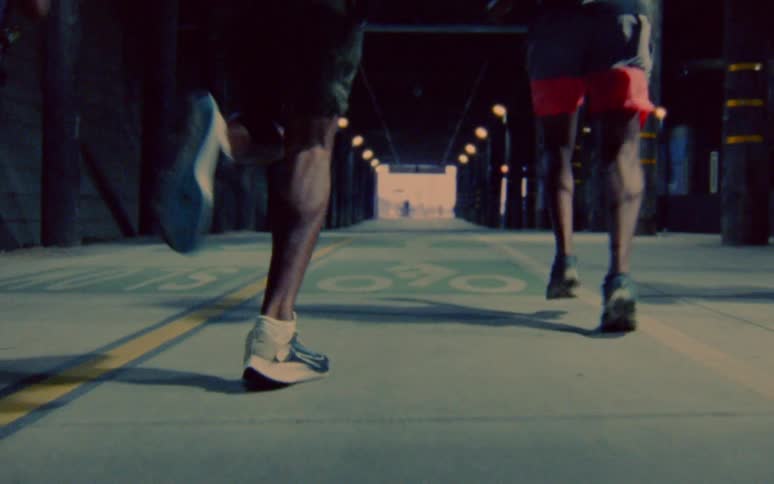 Three men jogging on concrete inside a structure