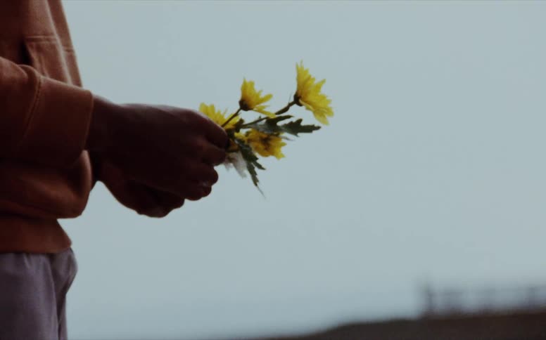 A man holds yellow flowers in his hands
