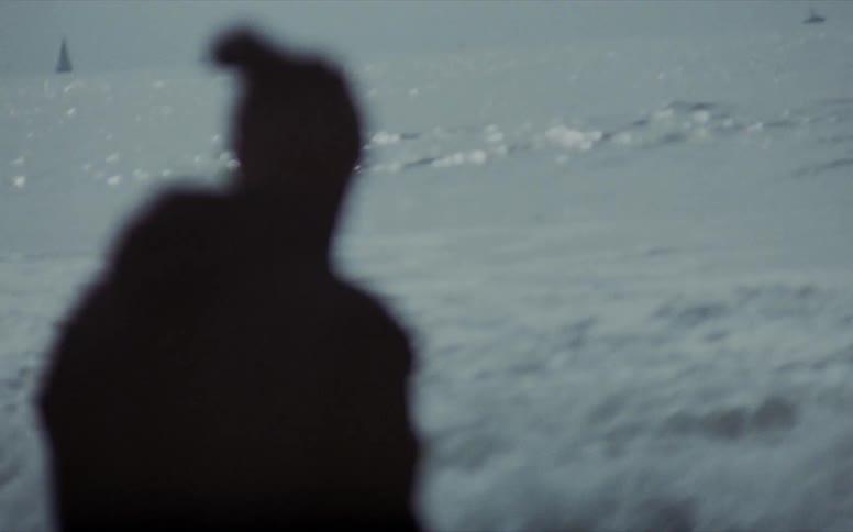 A person is standing on an ocean beach as waves are rolling and crashing in