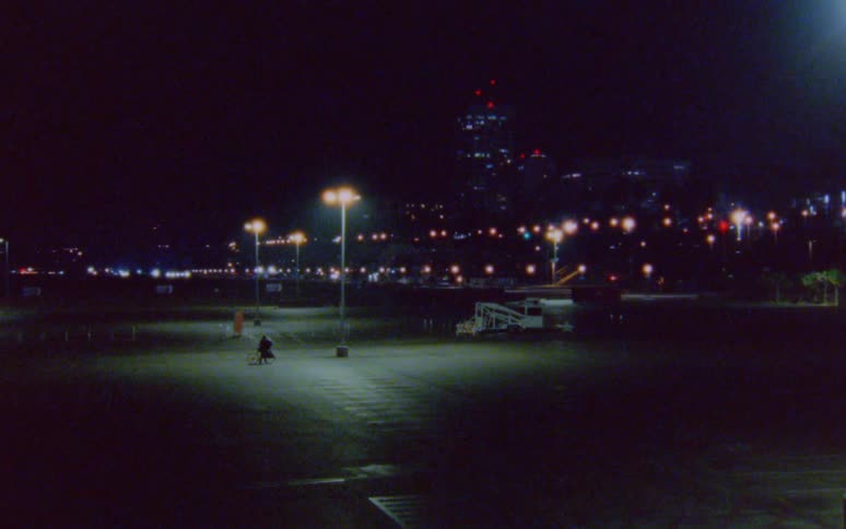 Person walking with a bicycle on an empty parking lot near the city caught on vintage film