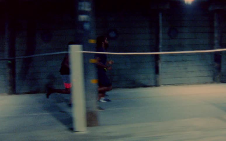 Two men are jogging together in a city at night