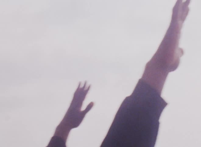 Close up of a persons arms raised up in the air
