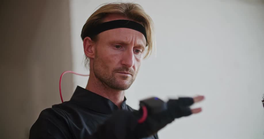 A man has virtual reality devices on his hand and he is looking at his hand as he movies it