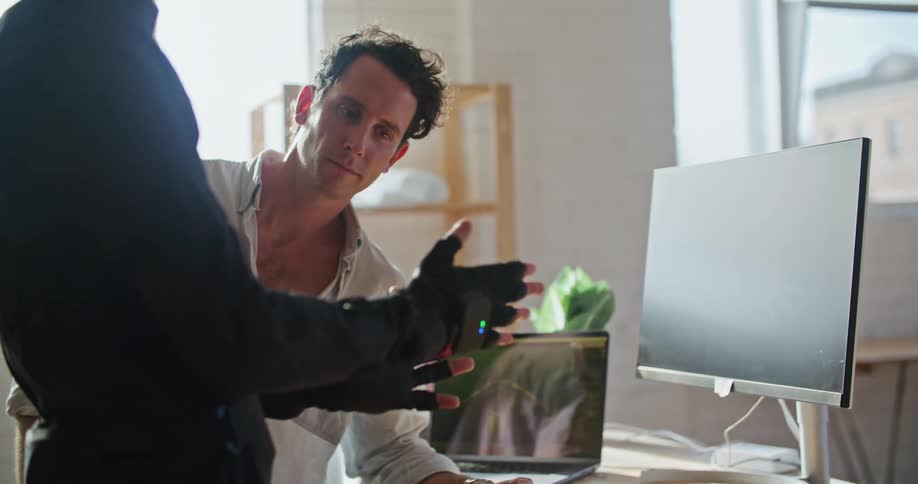 Man in white shirt gives instructions to another man wearing a futuristic motion capture black suit