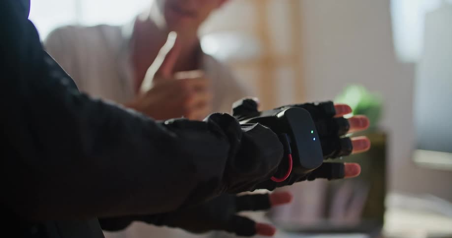 A person wearing motion detection gloves opens and closes their hand while working with a colleague