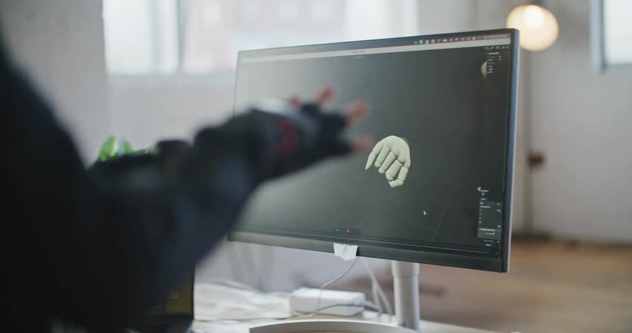 Man wearing a motion capture suit test his hand movements on a computer screen