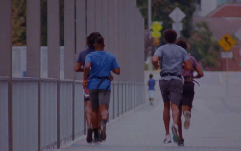 Four men are running together on the sidewalk