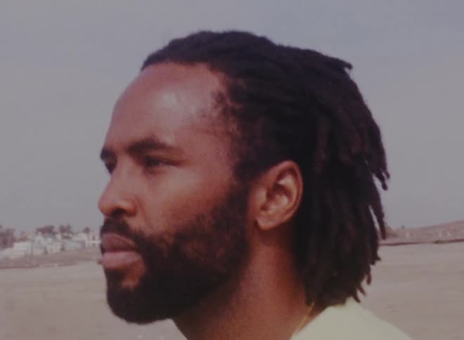 A black man is outside in a desert area