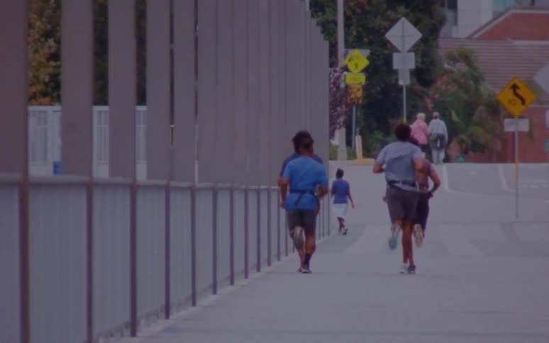 A group of men jog together through a city during the day