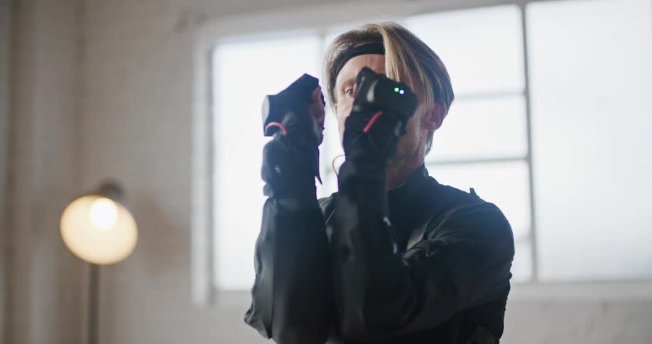 A man wearing interactive computer virtual reality devices is practicing martial arts movements