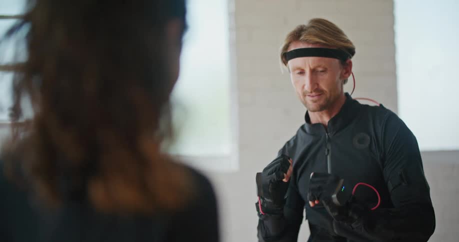 Young fit woman teaching boxing moves to a man wearing a motion capture suit