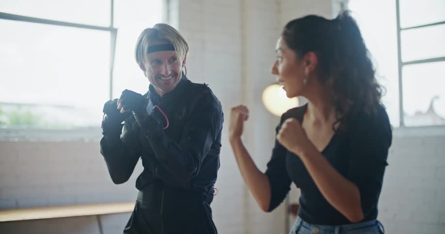 Young fit woman teaching boxing moves to a man wearing a motion capture suit