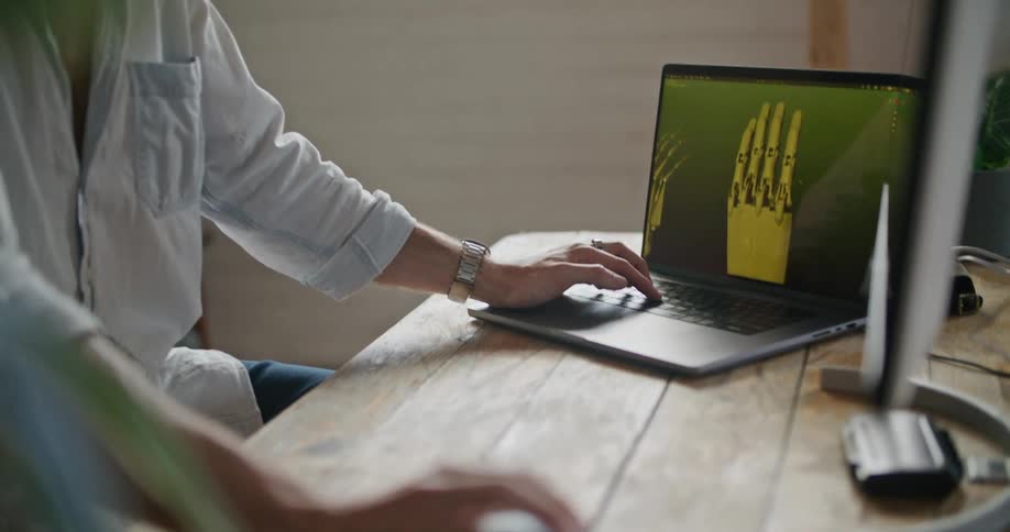 Man wearing a white shirt working on computer models on a laptop and a computer