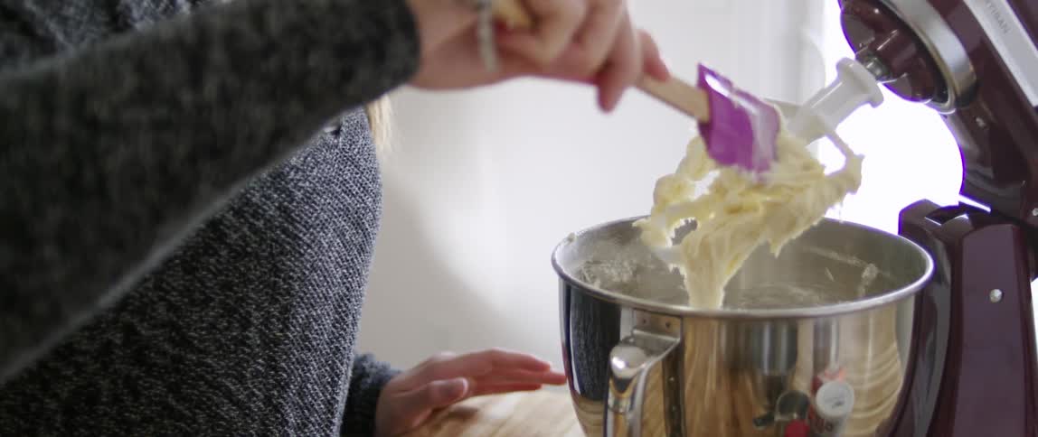 Woman removing dough from her blender