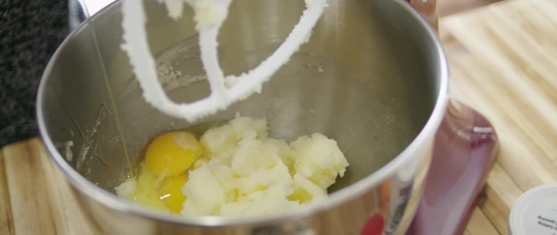 Person cracking eggs into a mixing bowl