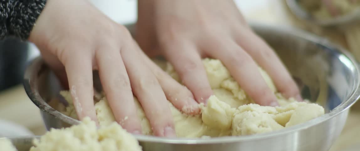 Young girl uses her hands to finish mixing the ingredients