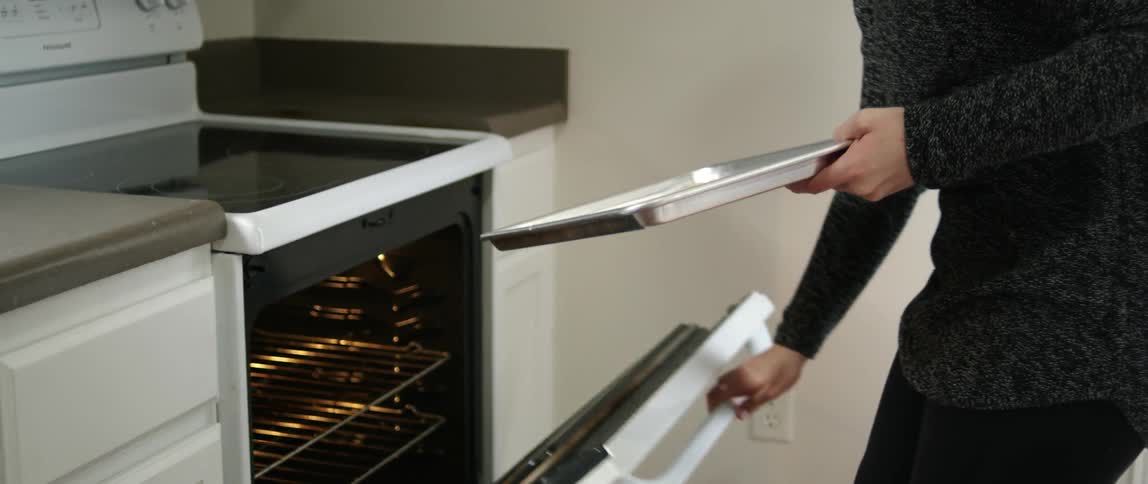 A person puts cookies in the oven