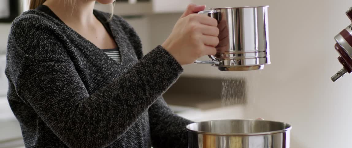 A woman is pouring sugar into a bowl