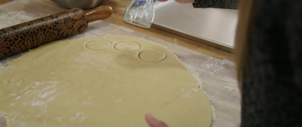 A person uses a cup as a cookie cutter