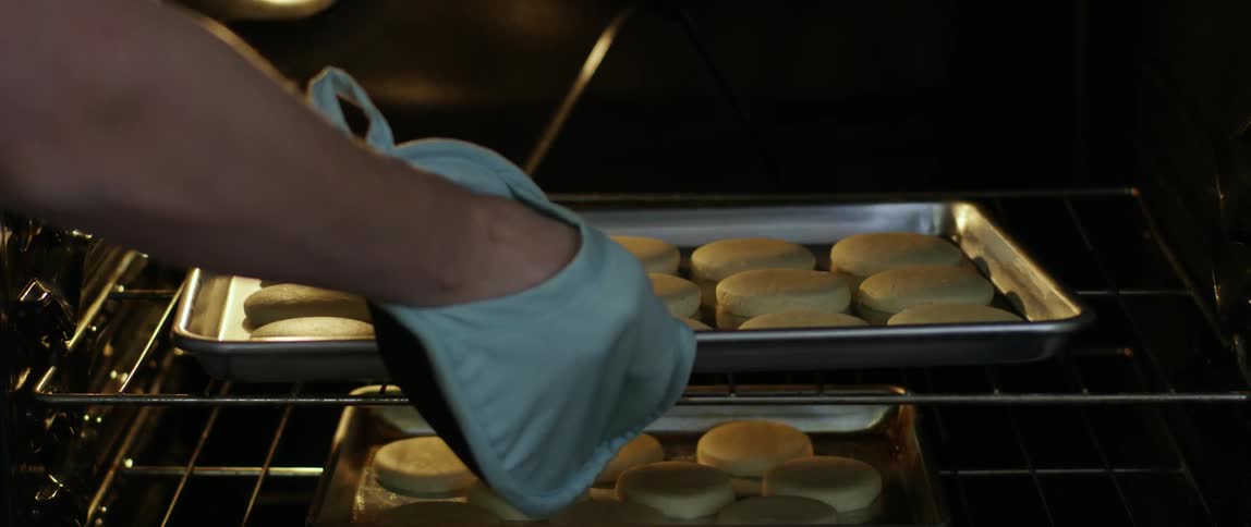 A person removes one tray of food from the oven