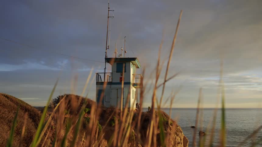 Person sits near watchtower on low promontory overlooking water